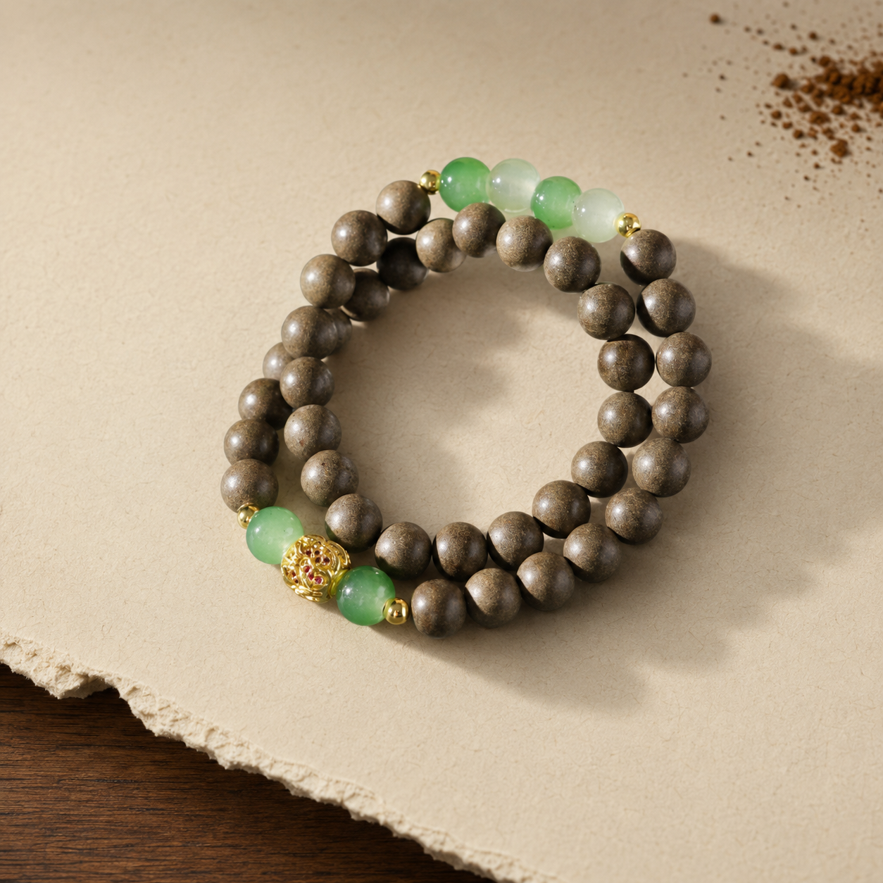 Double-wrap brown He Xiang bracelet with translucent green beads and a gold-toned openwork focal bead