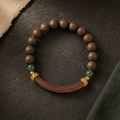 Brown He Xiang bracelet with green accent beads, gold-toned spacers and a curved translucent decorative component