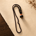 Dark braided He Xiang pendant necklace with a single aromatic bead, plum accents and an orange-red spacer