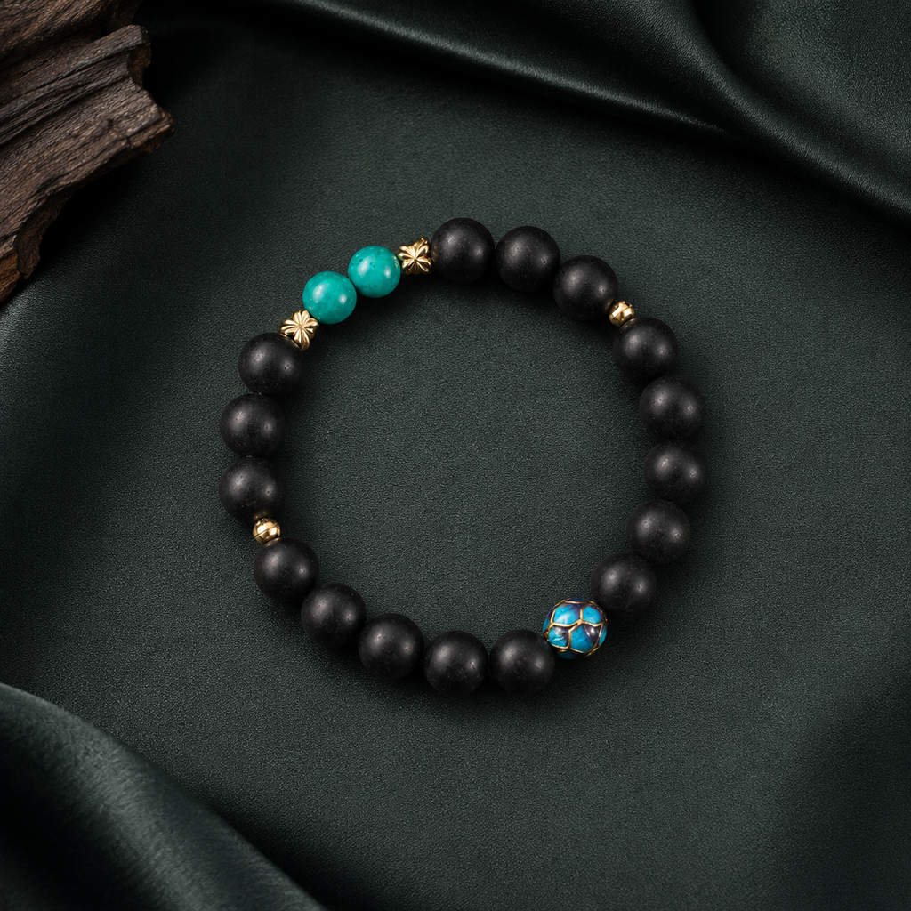 Valley Orchid He Xiang bracelet with matte black aromatic beads, turquoise accents and a blue enamel feature bead