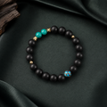 Valley Orchid He Xiang bracelet with matte black aromatic beads, turquoise accents and a blue enamel feature bead