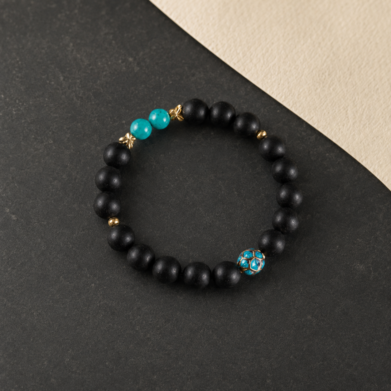 Valley Orchid He Xiang bracelet with matte black aromatic beads, turquoise accents and a blue enamel feature bead